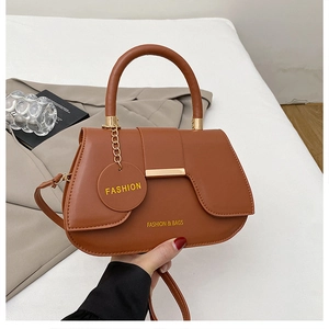 Close-up of brown leather saddle bag with gold metal clasp and hanging fashion tag