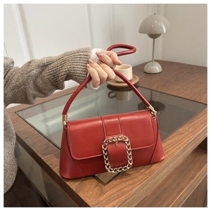 Close-up of deep red vintage baguette bag with a bold gold chain-style buckle detail