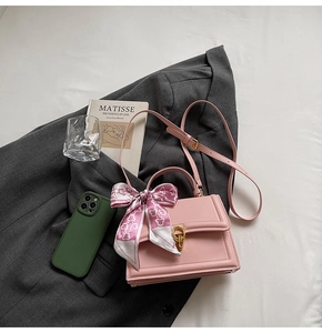 Detailansicht einer rosa Lederhandtasche mit Goldschloss und dekorativem Herz-Seidenschal