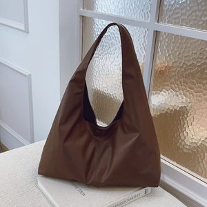 Minimalist large brown leather tote bag for women shown on art books in a bright setting