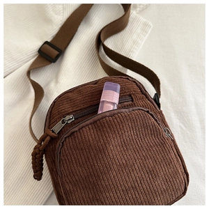 Detail of brown corduroy crossbody bag with zipper pocket and braided puller detail