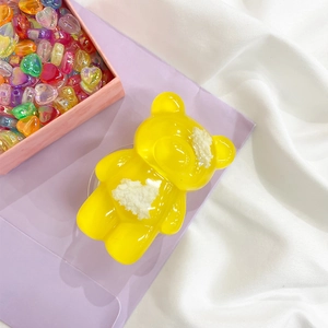 Detail of cute yellow bear phone grip with cream glue texture on a purple background
