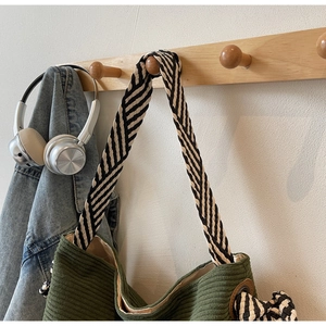 Détail du sac fourre-tout en velours côtelé vert foncé avec bandoulière tissée à rayures
