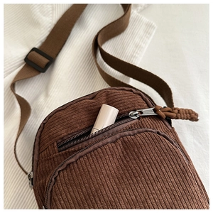Close-up of brown corduroy crossbody bag with zipper pocket and adjustable strap