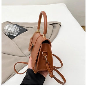Close-up of caramel faux leather saddle bag with round handle and metallic D-ring details