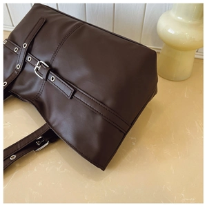Close-up of vintage dark brown tote bag showing smooth faux leather and silver metal buckles