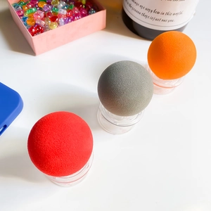 Detailed view of matte volcanic stone oil-absorbing rollers in three colors on clear stands