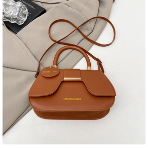 Detail view of vintage brown leather saddle bag with gold hardware and top handle