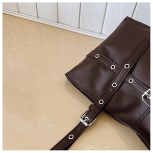 Close-up of vintage brown leather tote bag with silver eyelets and buckle details