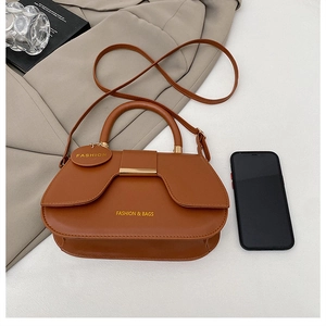 Detail showing brown leather saddle bag with golden metal buckle and brand tag