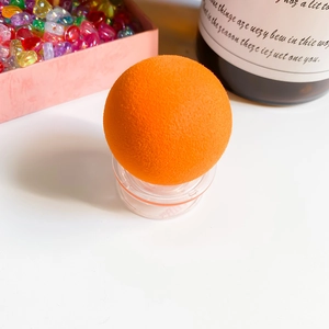 Macro detail of soft orange spherical makeup sponge on a clear desktop stand