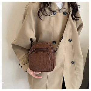 Detail view of the brown corduroy crossbody bag with multiple zip pockets on a model