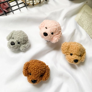 Close-up of four colorful plush teddy dog phone grips on aesthetic white fabric background