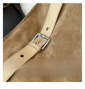 Gros plan d'un sac en daim marron avec bandoulière en cuir et boucle en métal argenté
