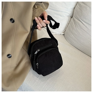 Detail of black corduroy crossbody bag texture and dual zipper compartments