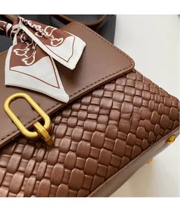 Close-up of woven leather texture and gold buckle on a retro dark brown crossbody bag