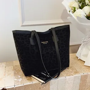 Elegant black leopard print tote bag with gold logo shown in a lifestyle setting