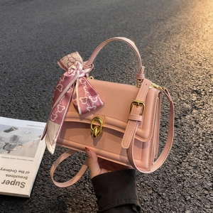 Rosa Lederhandtasche mit Goldschnalle und Seidenschal auf der Straße mit Magazin