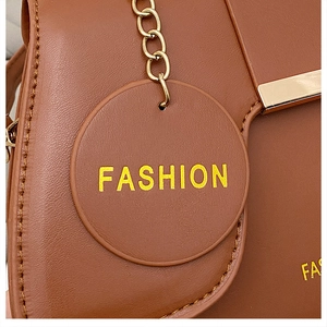Macro detail of brown leather saddle bag with gold metal hardware and fashion tag