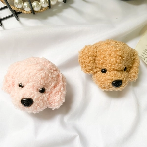 Close-up of cute pink and caramel plush teddy dog phone grips on soft fabric background