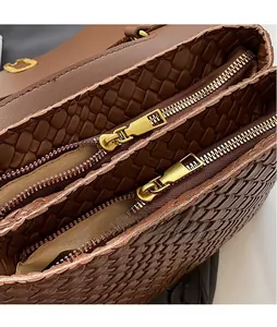 Detail of woven brown leather texture and dual golden zippers on stylish handbag