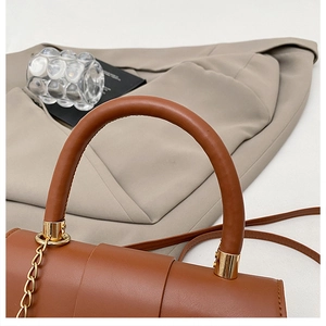 Detail view of the brown leather saddle bag with round handle and gold metal hardware