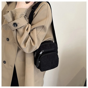 Détail d'un sac bandoulière en velours côtelé noir avec double fermeture éclair et sangle