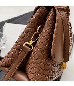 Detailed macro shot of dark brown woven leather texture with gold metal swivel hook