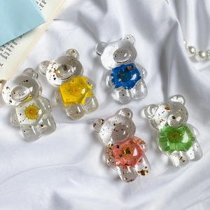 Close-up of bear-shaped phone grips with embedded dried flowers and gold leaf foil