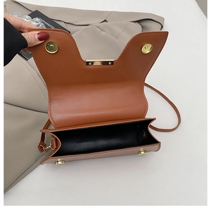 Detail view of brown saddle bag with golden magnetic clasp and textured faux leather finish
