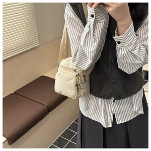 Detail of beige corduroy crossbody bag with multiple zip pockets and woven pullers