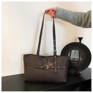 Close-up of deep brown leather tote bag with metal buckle straps and silver eyelet details