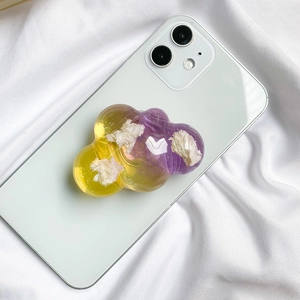 Detail of glitter cloud phone grip with purple-yellow gradient on a white smartphone