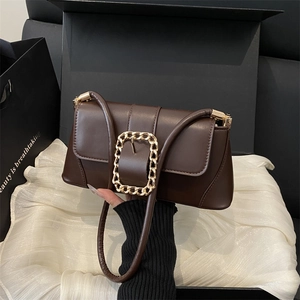 Deep brown rectangular baguette bag with gold chain buckle in a luxury gift box setting