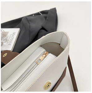 Dettaglio ravvicinato della borsa a secchiello bicolore con chiusura magnetica e zip oro