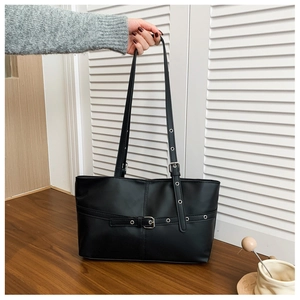 Detail of black leather tote bag with silver metal buckles and adjustable shoulder strap