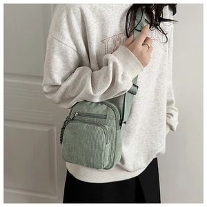 Detail of light green corduroy crossbody phone bag with zipper pockets and adjustable strap