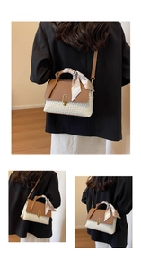 Detail of two-tone woven handbag featuring a silk scarf wrap handle and gold buckle