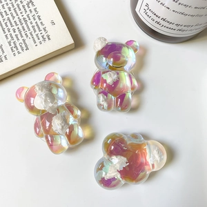 Three gradient cloud bear phone socket stands displayed on a table with props