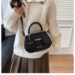 Close-up of black PU leather saddle bag with gold hardware and brand tag on a model