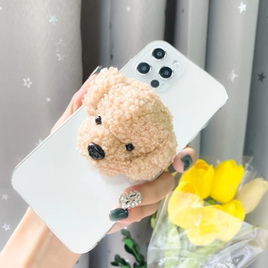 Close-up of cute plush teddy dog phone grip on a white case held in hand