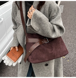 Détail de la bandoulière en daim marron avec boucle en métal vintage sur manteau en laine