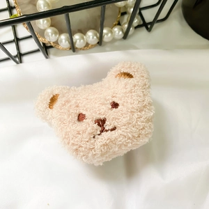 Close-up of soft plush bear phone grip with curly faux sheepskin texture and embroidery