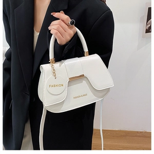 Close-up of white semi-circular PU leather bag with gold buckle and fashion text