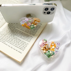 Detail of heart-shaped phone grip featuring 3D cartoon animal figures on a white smartphone