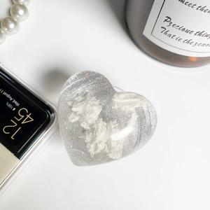 Detailaufnahme einer herzförmigen Glitzer-Handyhalterung mit Wolke auf Smartphone