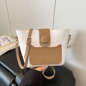 Borsa a secchiello bicolore minimalista in bianco e marrone su sedia di pelle