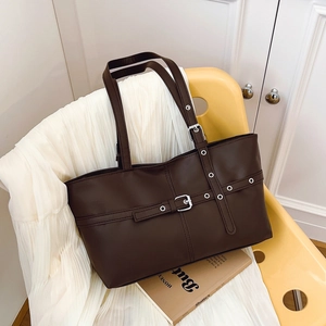 Vintage large capacity brown leather tote bag with buckle straps on a yellow chair