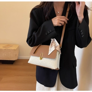 Detail of white woven texture shoulder bag with brown flap and elegant printed silk scarf