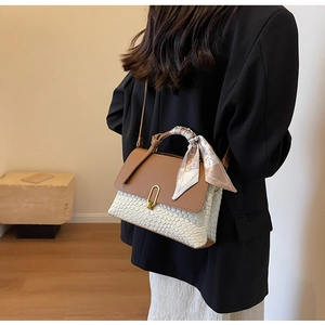 Detail view of woven leather handbag with gold twist lock and printed silk scarf on handle